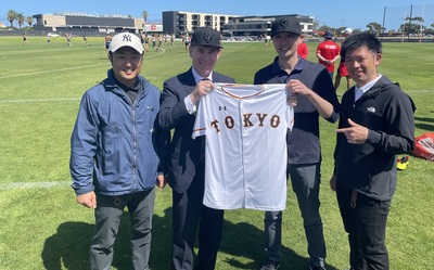 Minister for Trade and Investment Nick Champion with members of the Tokyo Giants baseball team, holding up a Tokyo Giants baseball shirt.